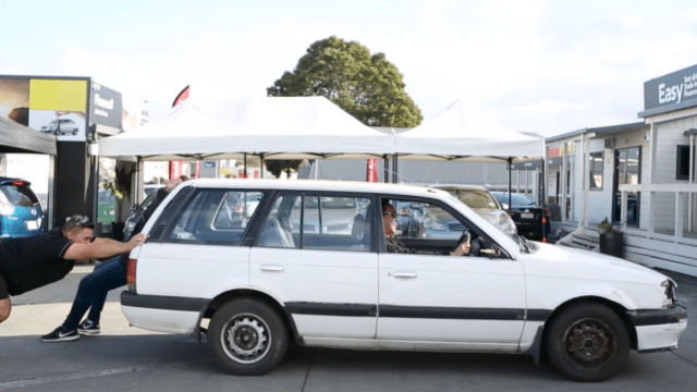 White station wagon being pushed at a car dealership yard